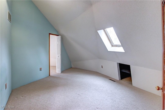 additional living space featuring lofted ceiling with skylight, visible vents, and carpet floors