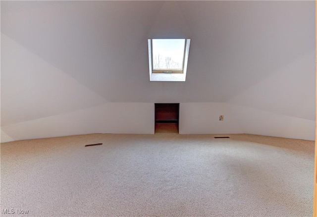 additional living space with lofted ceiling with skylight, visible vents, and carpet