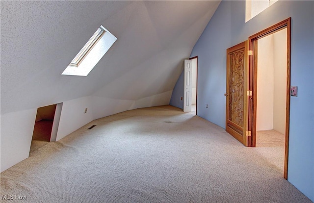 bonus room with visible vents, carpet floors, a textured ceiling, and lofted ceiling with skylight