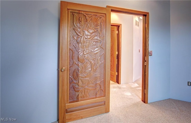 hallway featuring visible vents and carpet