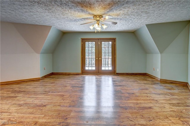 bonus room featuring french doors, baseboards, a textured ceiling, and wood finished floors