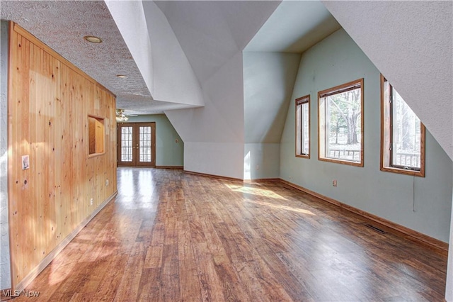 bonus room featuring visible vents, baseboards, vaulted ceiling, french doors, and wood finished floors