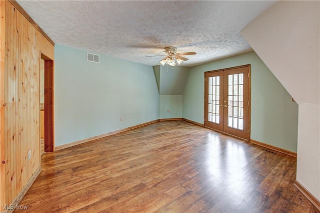 bonus room with wood finished floors, visible vents, french doors, and a textured ceiling