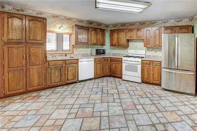 kitchen featuring tasteful backsplash, light countertops, brown cabinets, stainless steel appliances, and a sink