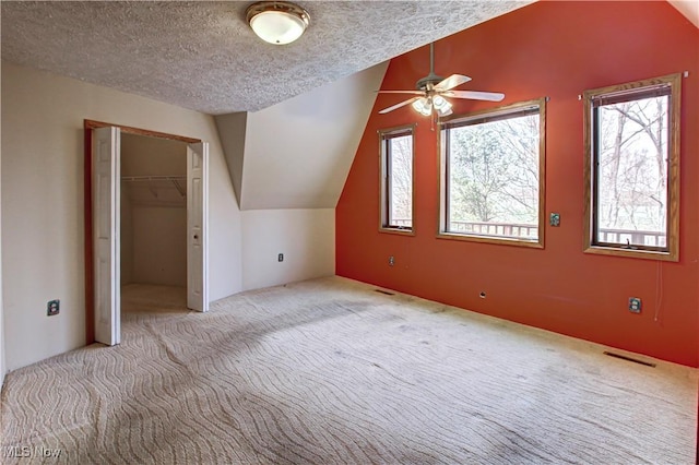 bonus room featuring vaulted ceiling, carpet flooring, a healthy amount of sunlight, and a textured ceiling