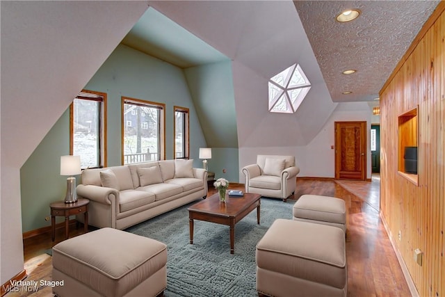 living room with wooden walls, baseboards, vaulted ceiling, hardwood / wood-style flooring, and a textured ceiling