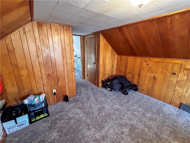 additional living space with lofted ceiling, wooden walls, and carpet