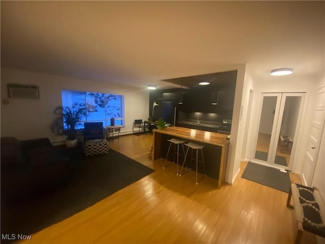 living room featuring a baseboard heating unit, wood finished floors, and a wall unit AC