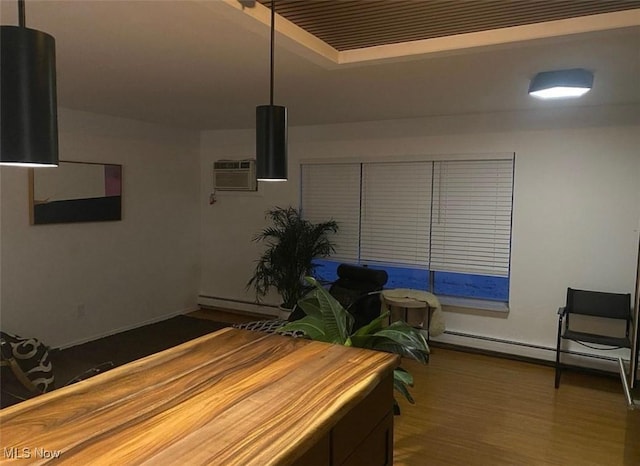 interior space with a raised ceiling, baseboard heating, and wood finished floors