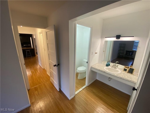 bathroom with a sink, baseboards, toilet, and wood finished floors