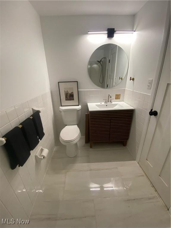 bathroom featuring toilet, tile walls, and vanity