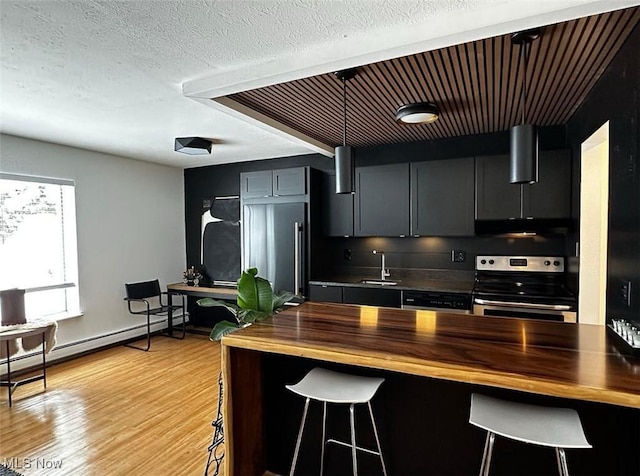 kitchen featuring light wood finished floors, a sink, stainless steel range with electric cooktop, a textured ceiling, and wood counters