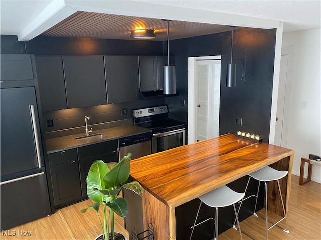 kitchen featuring a sink, dark countertops, appliances with stainless steel finishes, and light wood-style flooring