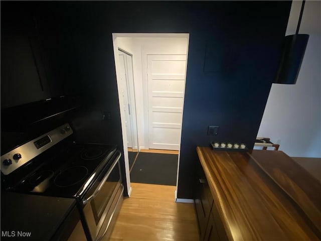 kitchen with electric range, light wood-style floors, and butcher block counters