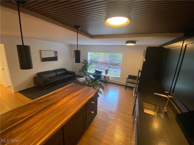 kitchen featuring light wood-style flooring, a raised ceiling, butcher block countertops, and open floor plan