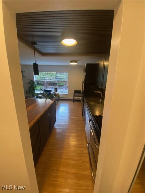 kitchen with a sink, light wood finished floors, and electric stove