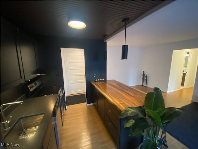 kitchen with wooden counters, light wood-style flooring, stainless steel electric stove, a sink, and decorative light fixtures