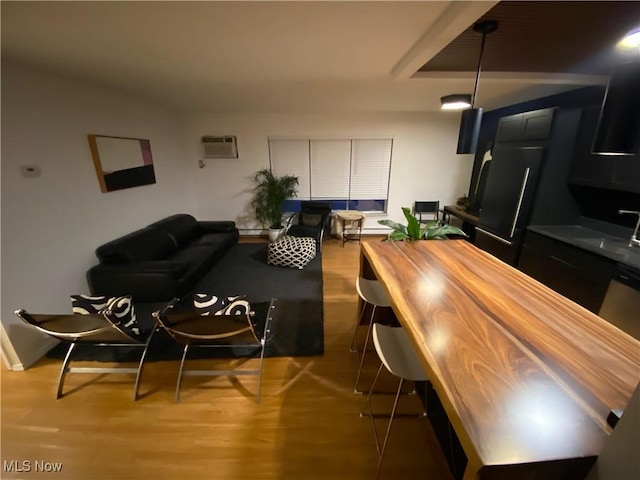 dining area with wood finished floors and a wall unit AC