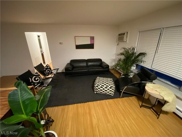 living area with an AC wall unit and wood finished floors