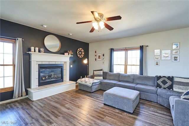 living area with a fireplace, a ceiling fan, and wood finished floors