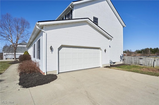 view of side of home featuring a garage, concrete driveway, and fence