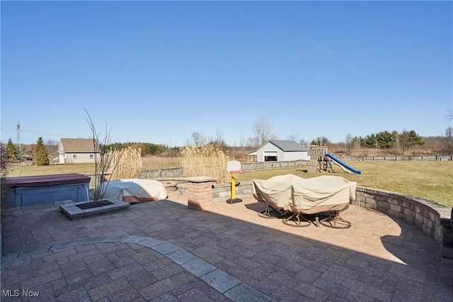 view of patio featuring a hot tub, a playground, and fence