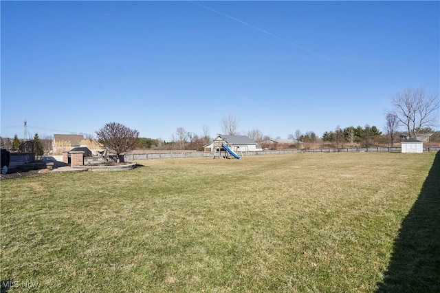 view of yard featuring an outdoor structure, a playground, a storage unit, and fence