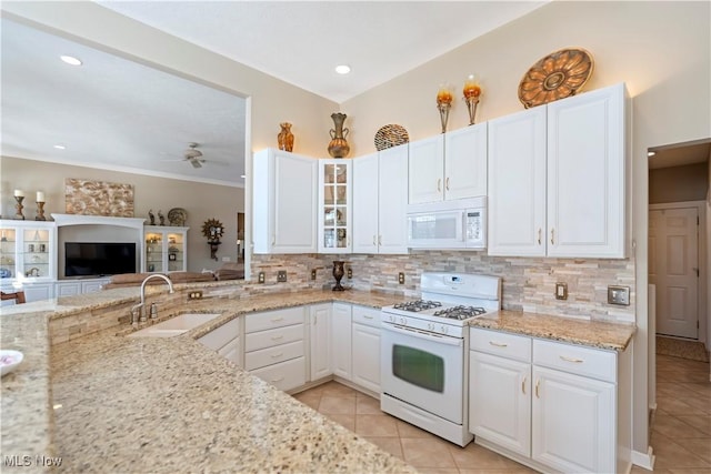 kitchen featuring white appliances, light stone countertops, a sink, white cabinets, and backsplash