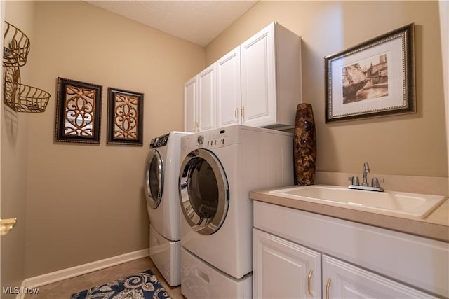 washroom with cabinet space, light tile patterned floors, washing machine and dryer, and a sink