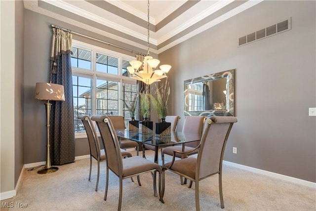 carpeted dining area featuring visible vents, a raised ceiling, ornamental molding, an inviting chandelier, and baseboards