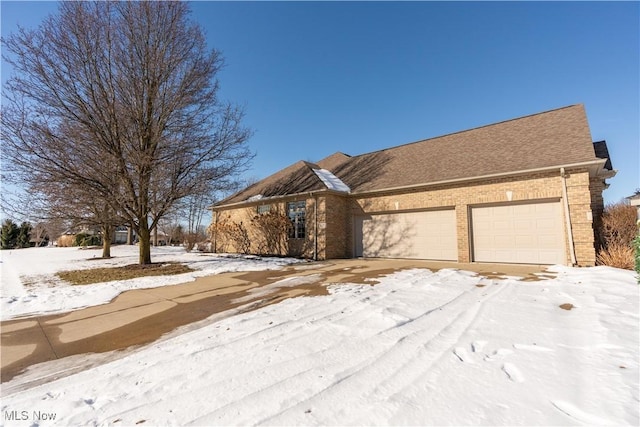 view of front of home with an attached garage, brick siding, and a shingled roof