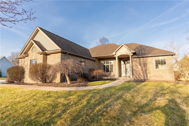 ranch-style home with a front lawn, brick siding, and a shingled roof