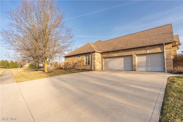 ranch-style house with a garage, brick siding, roof with shingles, and concrete driveway