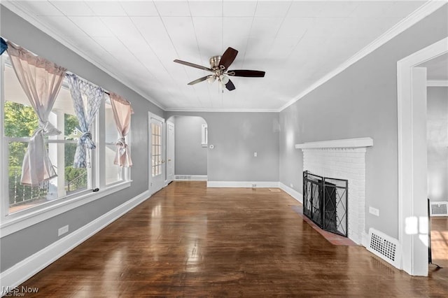 unfurnished living room with wood finished floors, visible vents, a fireplace, arched walkways, and ornamental molding