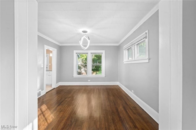 empty room featuring visible vents, dark wood-type flooring, crown molding, and baseboards