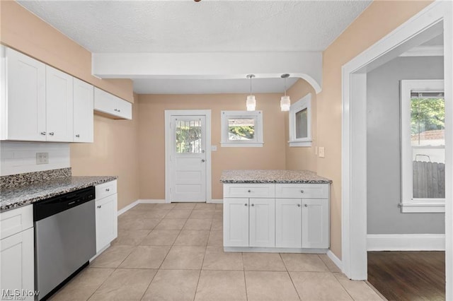 kitchen featuring stainless steel dishwasher, plenty of natural light, white cabinetry, and stone counters