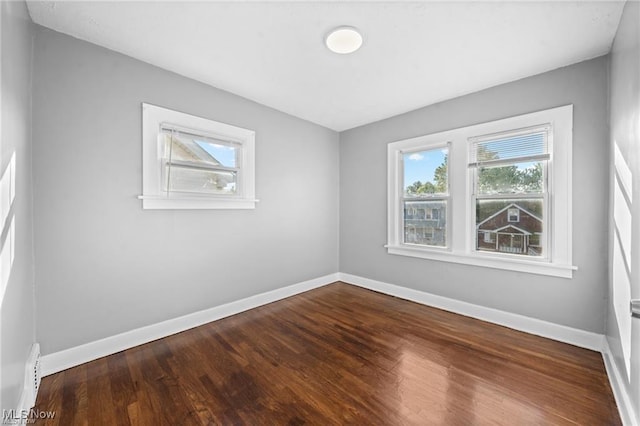 unfurnished room featuring a wealth of natural light, baseboards, and wood finished floors