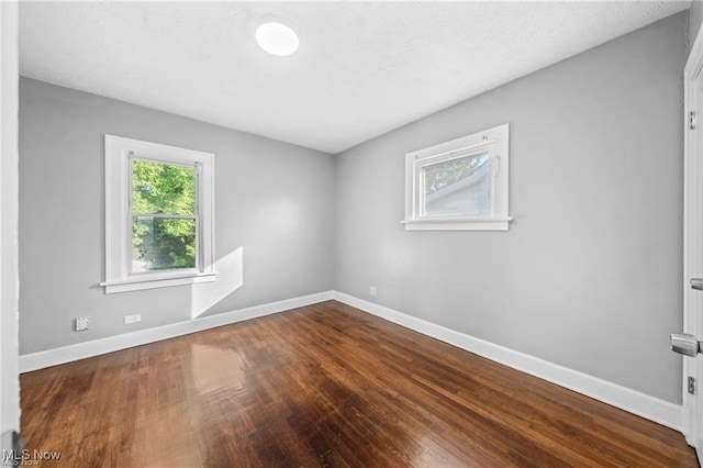 unfurnished room with baseboards, a textured ceiling, and wood finished floors