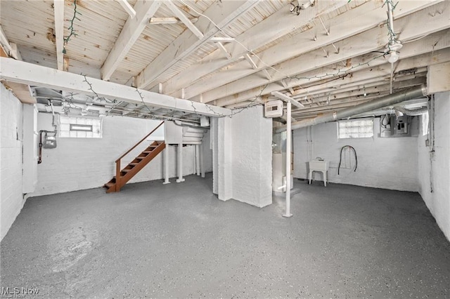 below grade area with a wealth of natural light, stairway, electric panel, and a sink