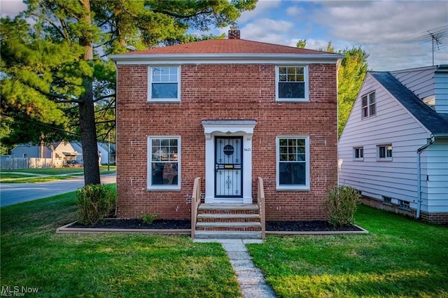 view of front of home with a front lawn, brick siding, and a chimney