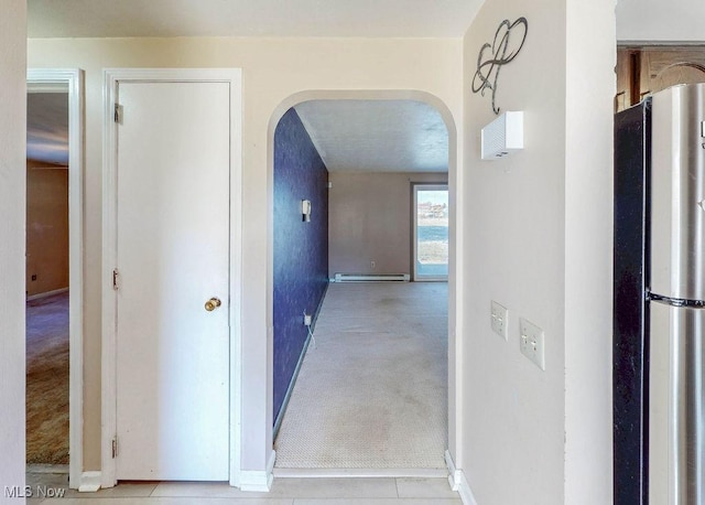 hall featuring a baseboard heating unit, arched walkways, and light carpet