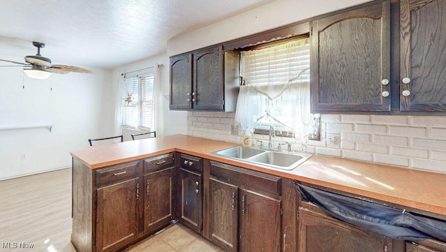 kitchen featuring decorative backsplash, a peninsula, light countertops, and a sink