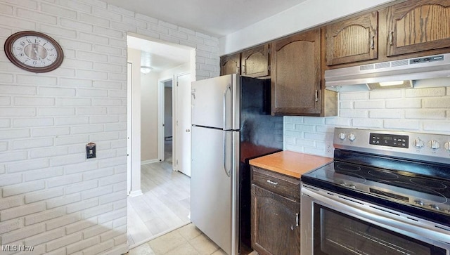 kitchen with under cabinet range hood, stainless steel appliances, light countertops, and tasteful backsplash