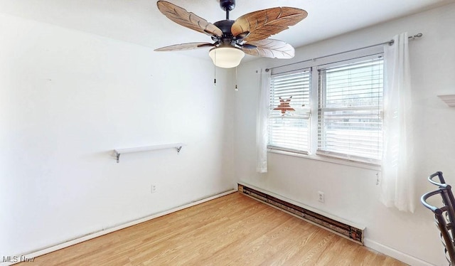 spare room featuring baseboard heating, wood finished floors, and a ceiling fan