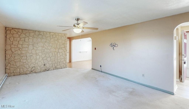 unfurnished room featuring arched walkways, carpet flooring, baseboards, and ceiling fan