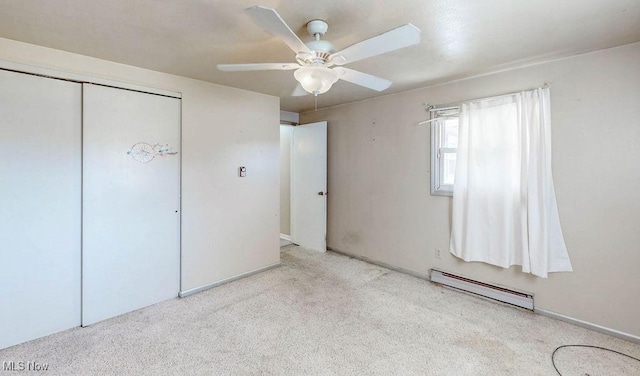 unfurnished bedroom with a closet, baseboard heating, a ceiling fan, and carpet