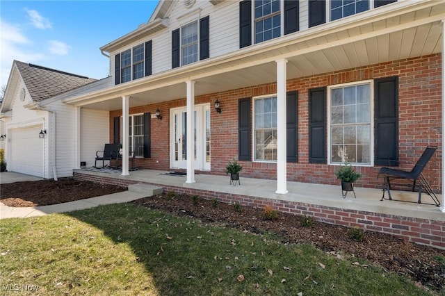 view of exterior entry with brick siding, a porch, and an attached garage