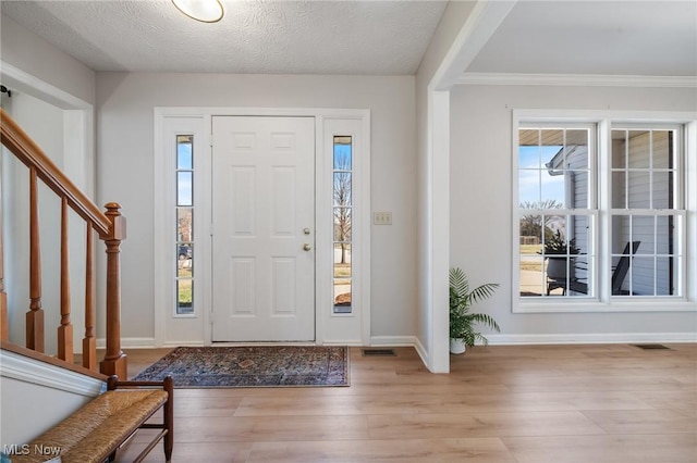 foyer featuring visible vents, baseboards, wood finished floors, and stairs