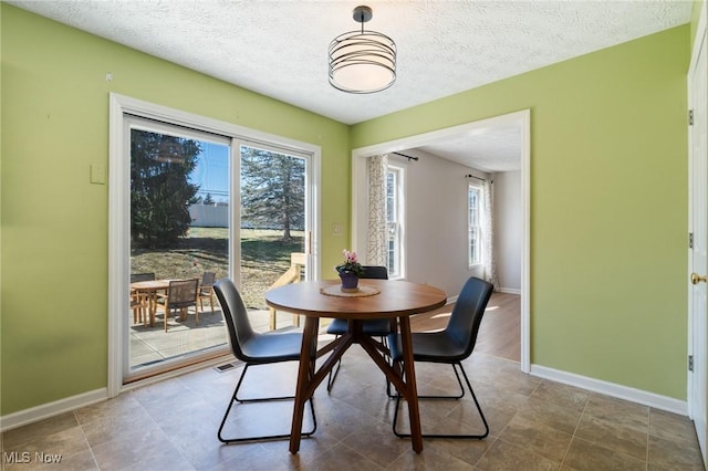 dining space with a textured ceiling and baseboards