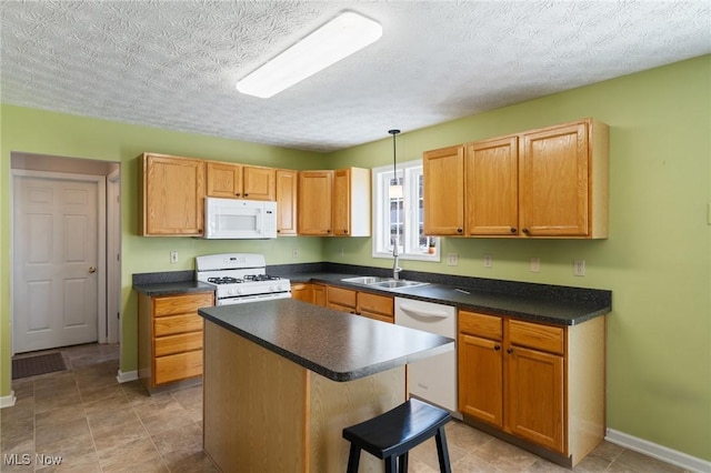 kitchen featuring dark countertops, a kitchen island, baseboards, white appliances, and a sink